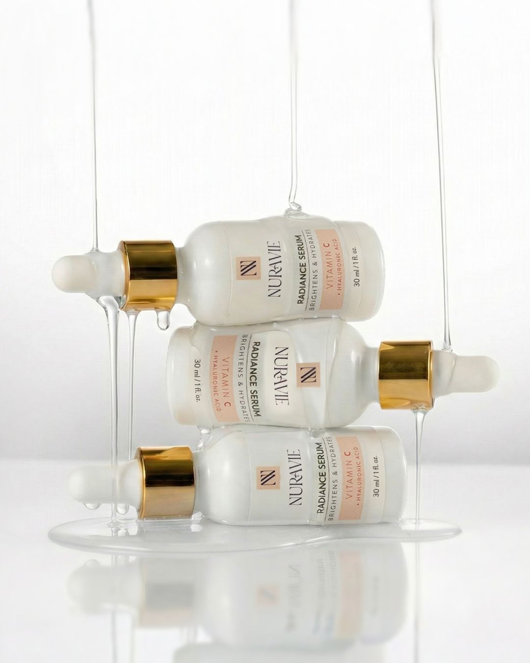 Three bottles of Nuravie Radiance Serum with gold caps on a white background