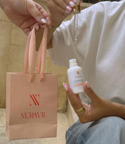 Person holding a bottle of Nuravie product with a pink bag in the background