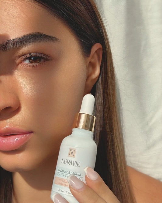Woman holding a Nuravie serum bottle close to her face