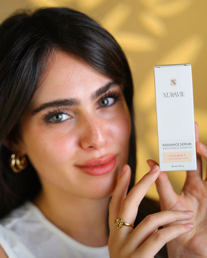 Woman holding a Nuravie radiance serum box against a blurred background